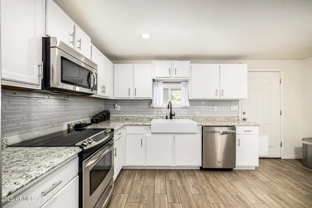 a kitchen with stainless steel appliances granite countertop a stove a sink and a microwave