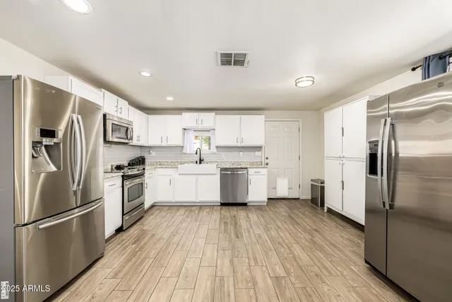 a kitchen with white cabinets stainless steel appliances and a refrigerator