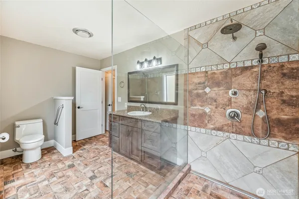 a bathroom with a granite countertop sink mirror vanity and toilet