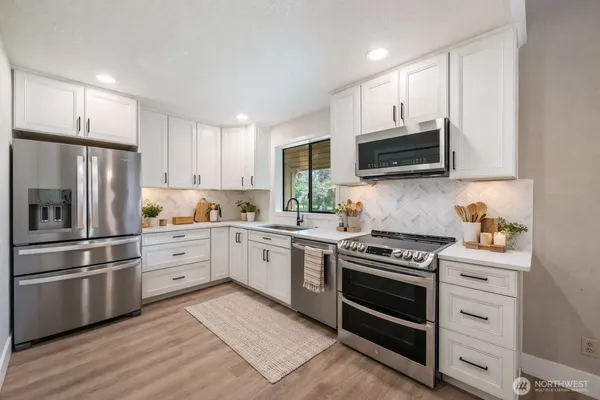 a kitchen with cabinets stainless steel appliances and wooden floor