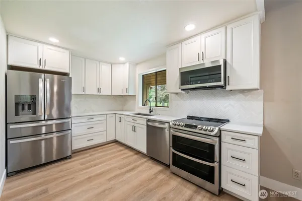 a kitchen with cabinets stainless steel appliances and wooden floor