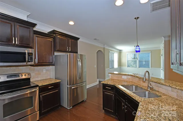 a kitchen with stainless steel appliances granite countertop a sink dishwasher a refrigerator and a stove with wooden floor