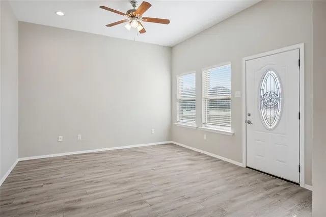 an empty room with wooden floor fan and windows