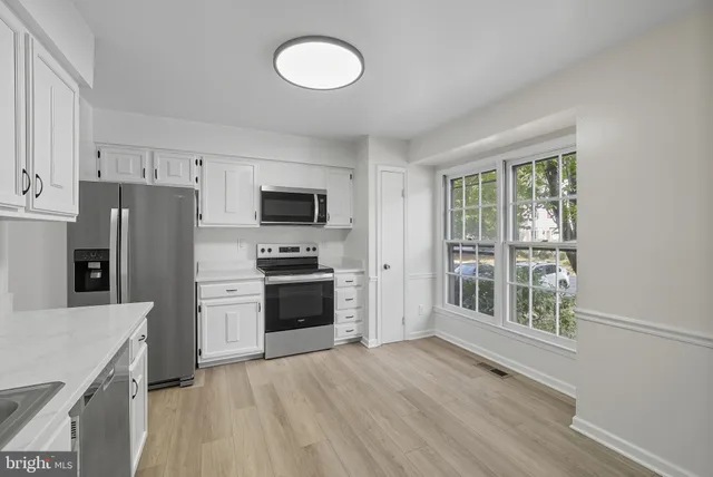 a kitchen with a refrigerator a stove top oven and a dishwasher with wooden floor