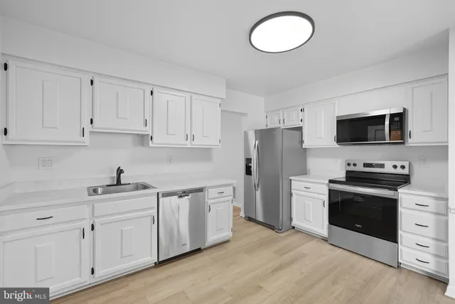 a kitchen with white cabinets stainless steel appliances and a sink