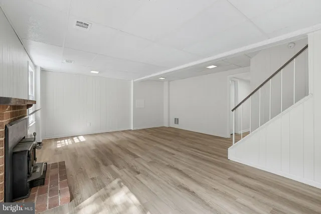 a view of an empty room with wooden floor and stairs