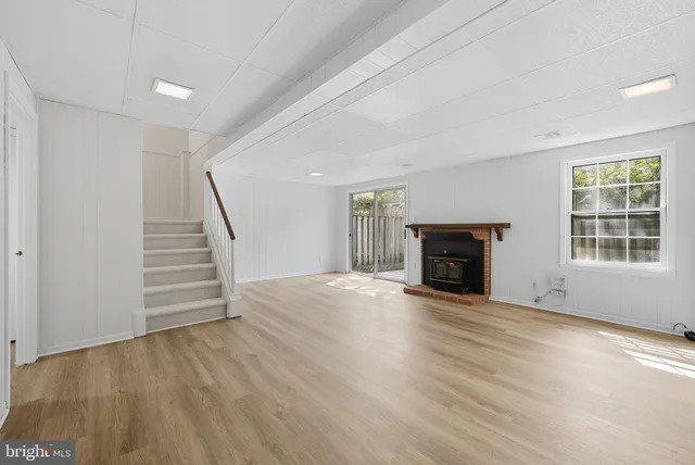 an empty room with wooden floor fireplace and windows