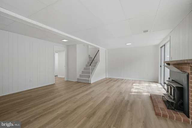 a view of an empty room with wooden floor and a fireplace