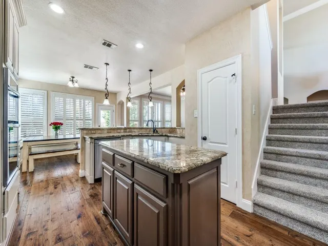 a kitchen with stainless steel appliances granite countertop a kitchen island a stove and a sink