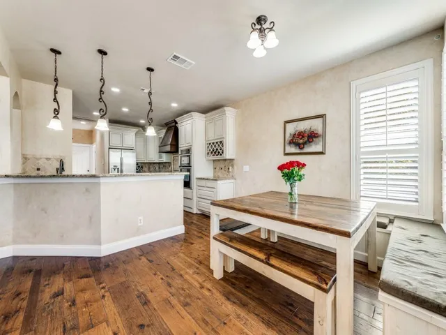 a large kitchen with stainless steel appliances granite countertop a stove a sink dishwasher and a dining table with wooden floor