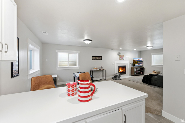1405 Vintry Lane Murray, UT 84121 - Photo 28 of 44 Lower level recreation area featuring a built-in fireplace with white mantel, recessed lighting, and multiple windows with blinds