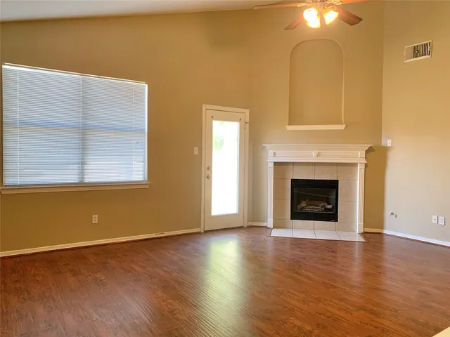 a view of an empty room with wooden floor and a fireplace