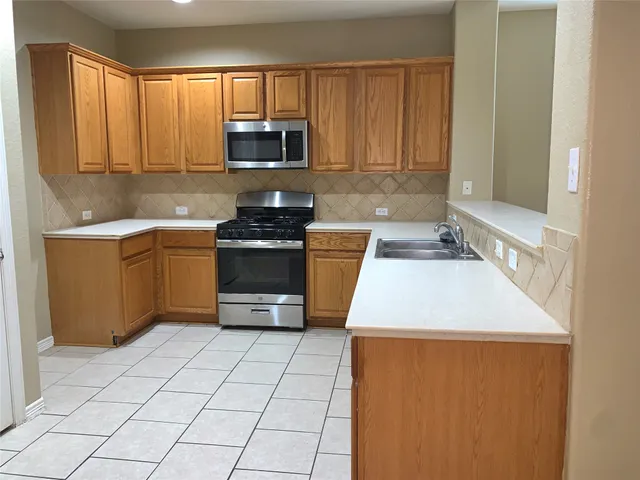 a kitchen with a sink a stove top oven and cabinetry