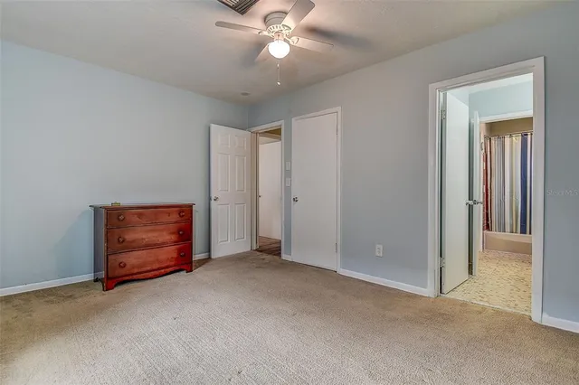 an empty room with closet and a chandelier fan