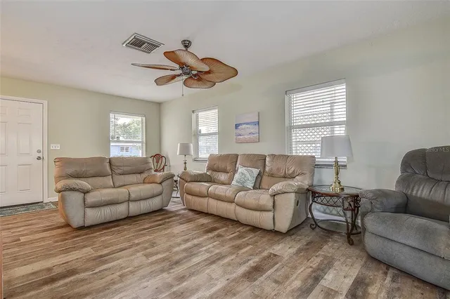 a living room with furniture a ceiling fan a lamp and a window