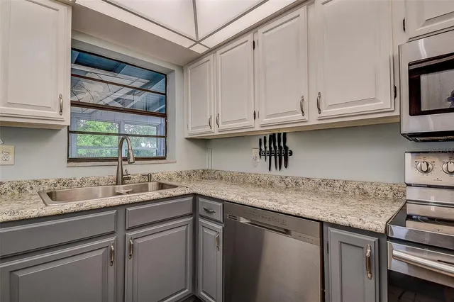a kitchen with stainless steel appliances granite countertop a sink window and cabinets