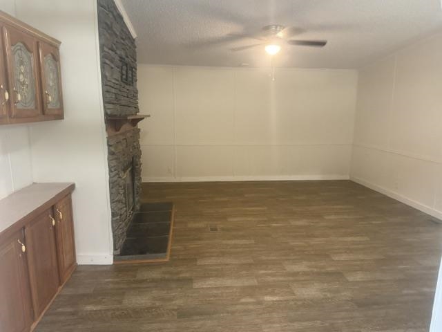 1100 Pine Top Road Toone, TN 38381 - Photo 10 of 40 Living area featuring wood-finish flooring, a stone-clad fireplace with a hearth, white paneled walls, a built-in ceiling fan with lighting, and built-in cabinetry with decorative hardware