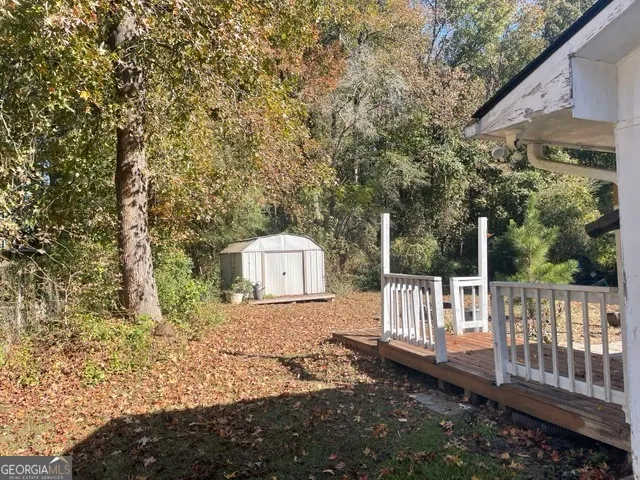 a view of a wooden house with a small yard and wooden fence