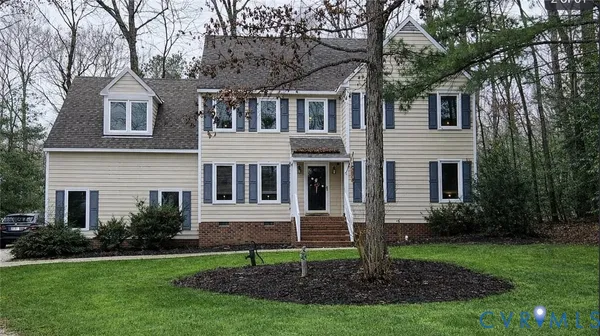 a view of a yard in front of a house with plants and large tree