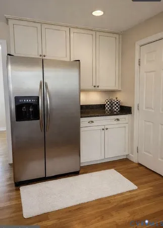 a kitchen with granite countertop a refrigerator a sink and white cabinets