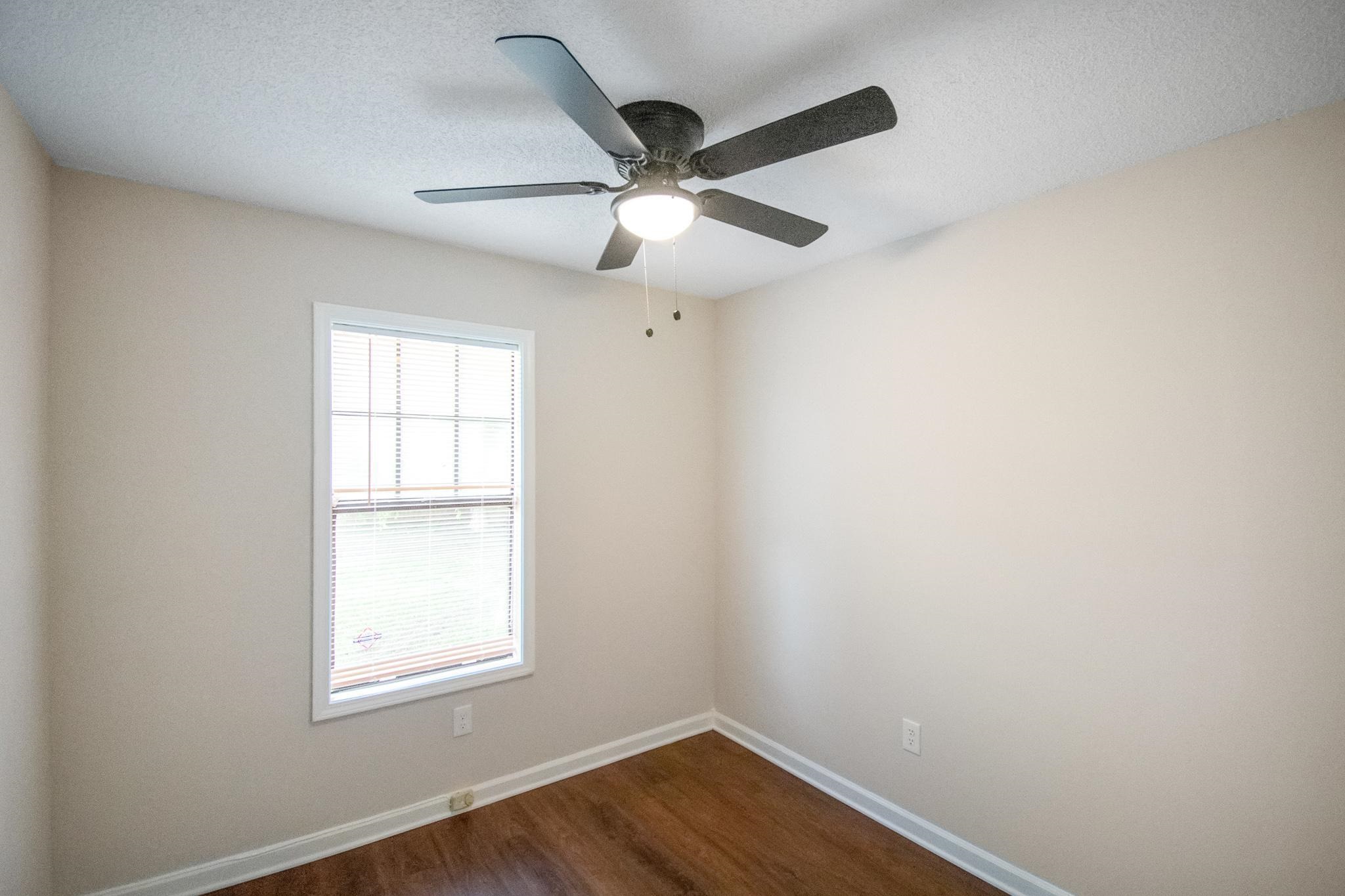 4775 Allrand Road Memphis, TN 38118 - Photo 16 of 21 an empty room with wooden floor ceiling fan and windows