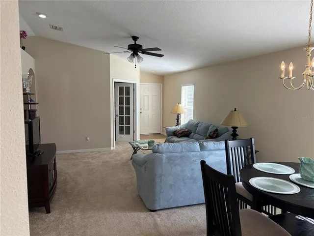 a living room with furniture a chandelier and a dining room