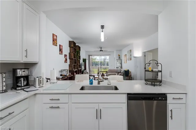 a kitchen with a sink dishwasher and white cabinets with wooden floor