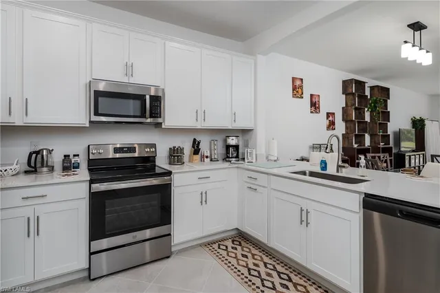 a kitchen with stainless steel appliances granite countertop a sink dishwasher a stove and white cabinets
