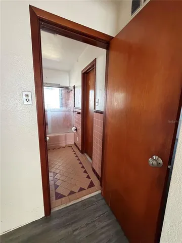 a view of a hallway with wooden floor and a bathroom