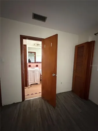 an empty room with wooden floor and a bathroom