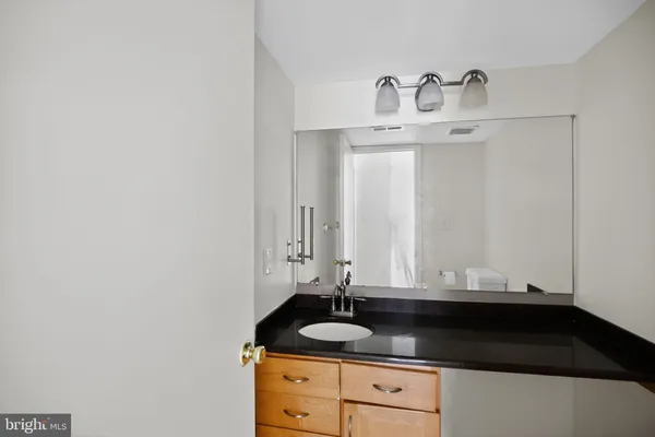 a bathroom with a granite countertop sink and a white cabinets