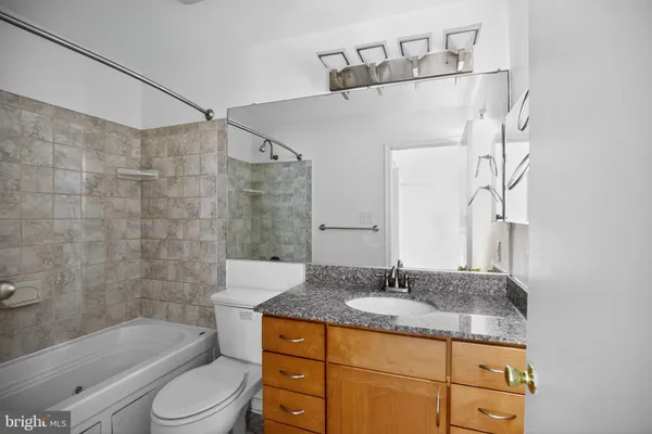 a bathroom with a granite countertop sink a toilet and bathtub