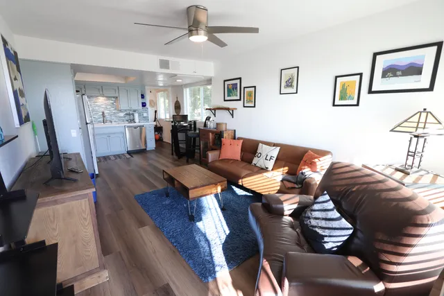 a living room with furniture kitchen view and a wooden floor