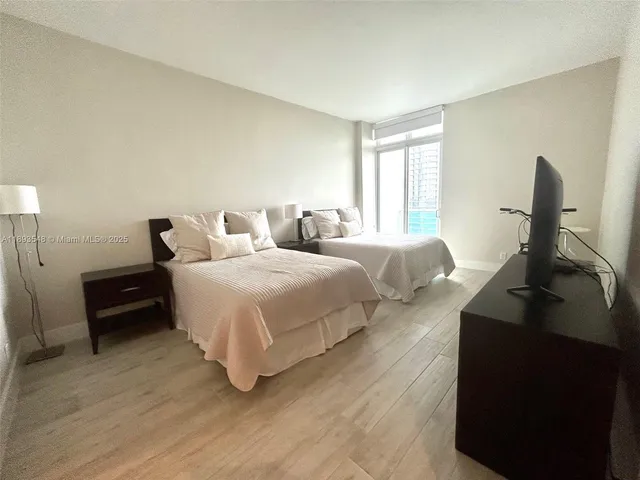 a bedroom with a bed a couch and a flat tv screen on a dresser