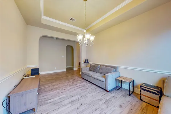 a living room with couches and a dining table with wooden floor