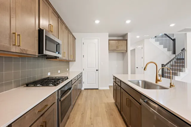 a kitchen with stainless steel appliances granite countertop a sink cabinets and wooden floor