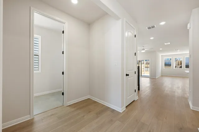 a view of a hallway with wooden floor and a kitchen