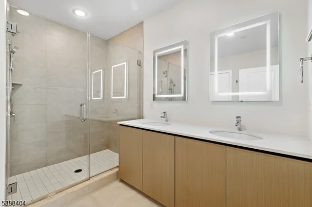 a bathroom with a double vanity sink mirror and shower