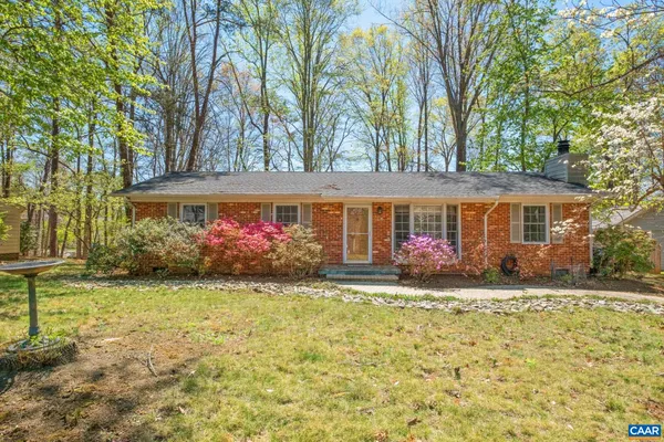 a front view of a house with a garden and trees