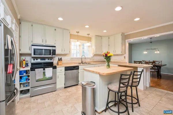 a kitchen with stainless steel appliances kitchen island granite countertop a stove top oven a sink dishwasher and a refrigerator with wooden floor