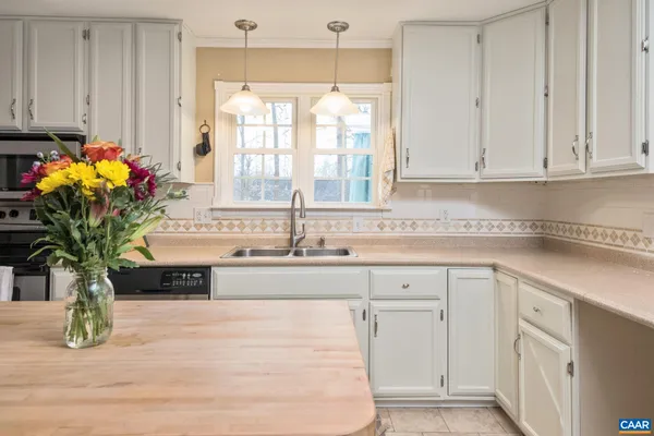 a kitchen with stainless steel appliances granite countertop a sink a white cabinets and a window