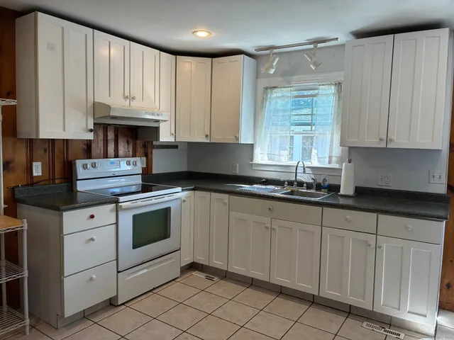 a kitchen with granite countertop white cabinets sink and stainless steel appliances