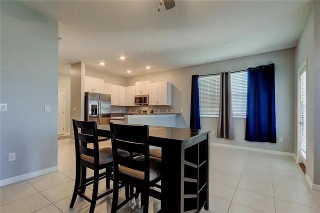 a kitchen with a dining table chairs and refrigerator