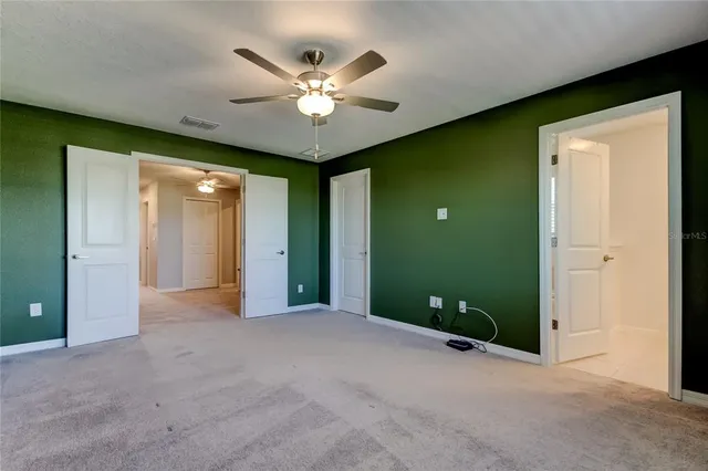 an empty room with chandelier fan and windows