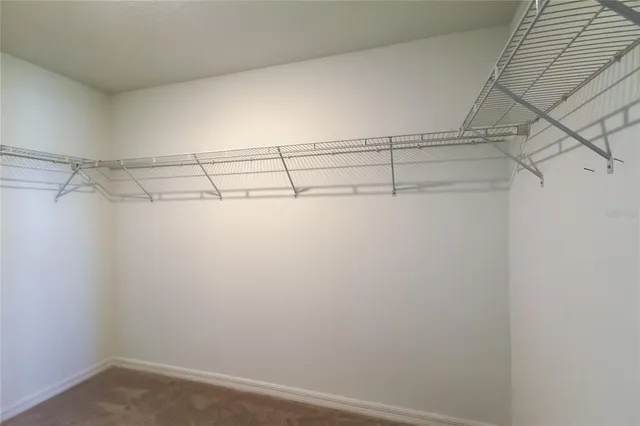 an empty room with chandelier fan and windows