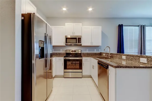 a kitchen with stainless steel appliances granite countertop a refrigerator stove and sink
