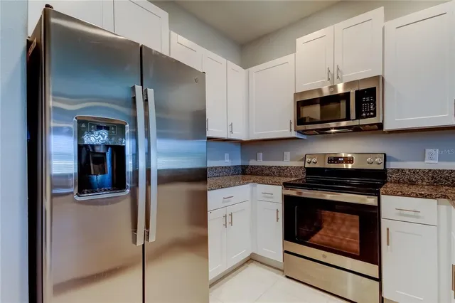 a kitchen with stainless steel appliances granite countertop white cabinets stove a microwave and a refrigerator