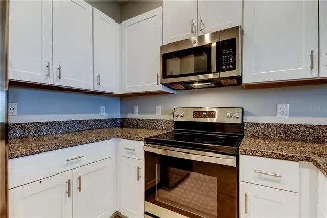 a kitchen with stainless steel appliances granite countertop grey cabinets a stove a sink and dishwasher