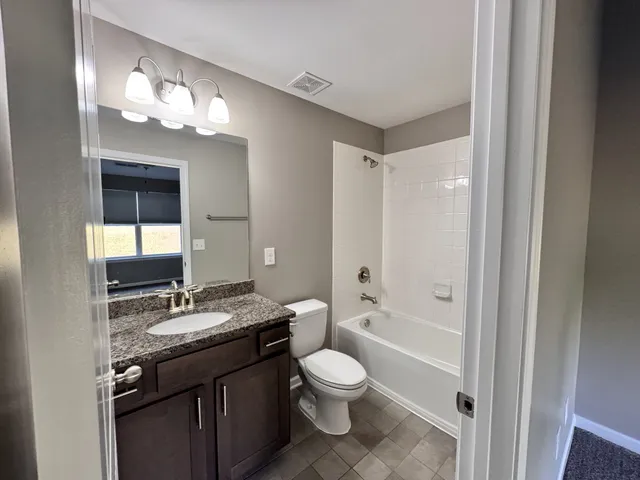 a bathroom with a granite countertop sink toilet a large mirror a shower and a bathtub