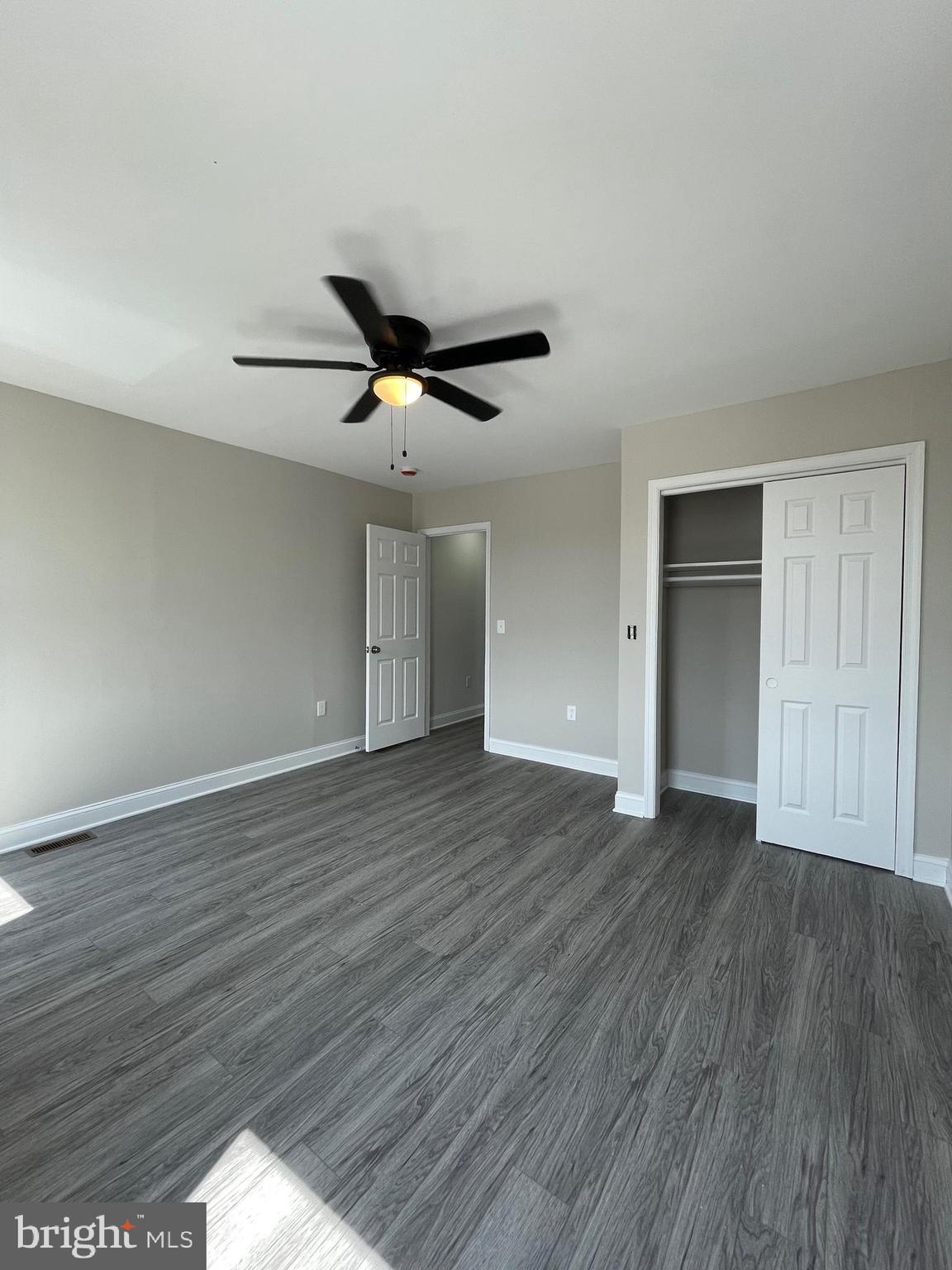 1806 East Lanvale Street Baltimore, MD 21213 - Photo 12 of 23 an empty room with wooden floor and a ceiling fan
